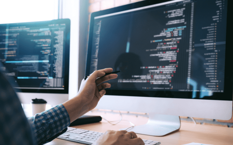 Senior software developers analyzing backend network configurations and writing source code for corporate application deployments.